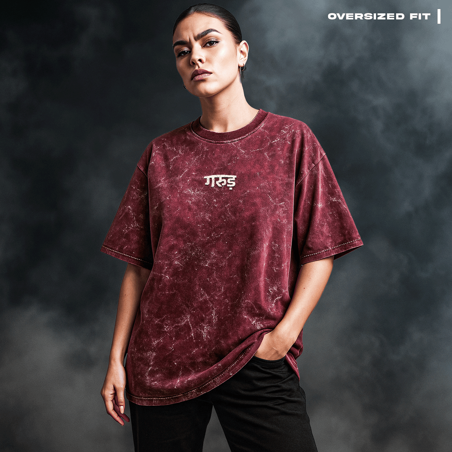 Person wearing an oversized maroon t-shirt with Garud on a dark background