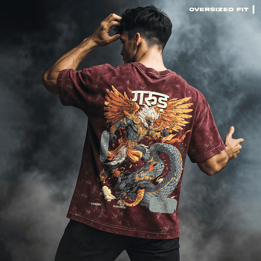 Man wearing Garuda: The Serpent Slayer T-shirt with a dragon and eagle design on the back against a dark background.