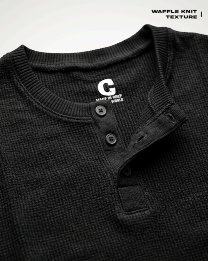 Close-up of a Waffle Knit Henley Full Sleeve T-shirt with a button placket and ribbed collar, showing a white 'G' logo on the inside neck label. Text in the top right reads 'WAFFLE KNIT TEXTURE'.